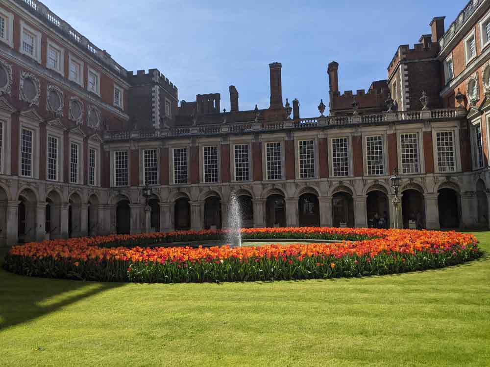 Ring of bright Tulips surrounding fountain at Hampton court Palace courtyard, Surrey, UK