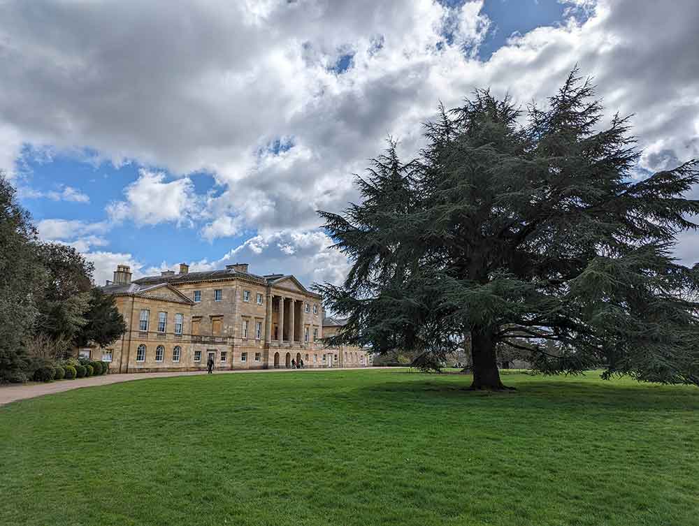 Stately home with large tree and lawn in foreground