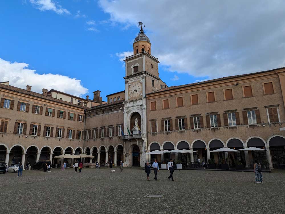 Cobblestoned Piazza Grande, fringed with umbrellas and cafes, Modena, Italy,