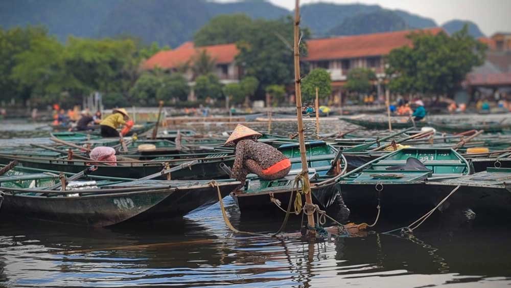 Woman crouching on a boat, Ninh Binh, Vietnam