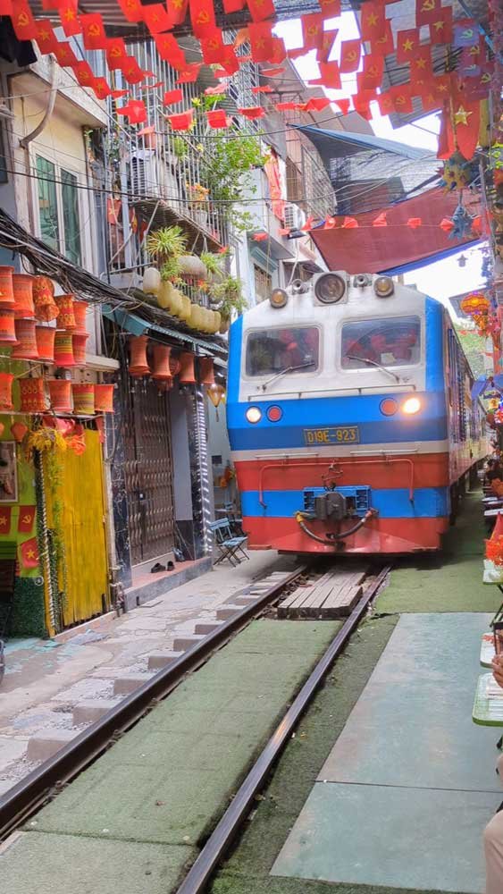 Train passing through brightly decorated Train Street, Hanoi, Vietnam