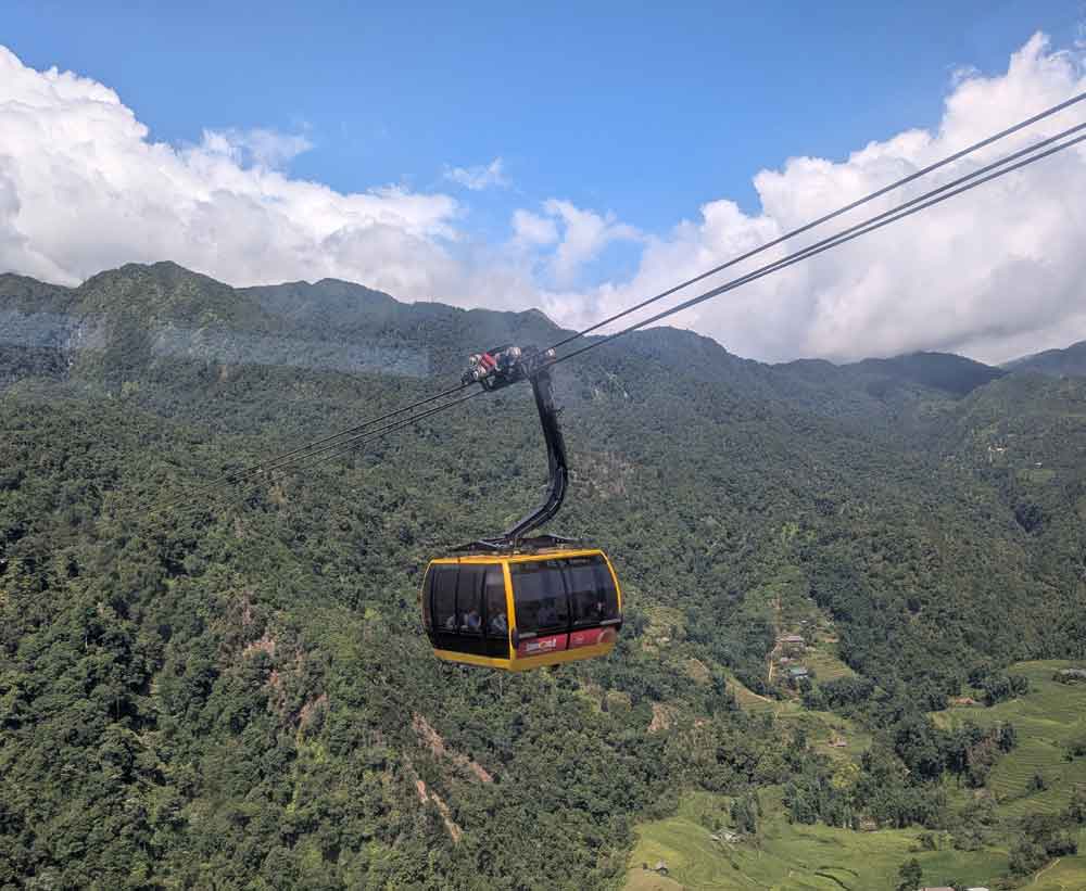 Yellow Cable car high above green mountains on way to Fansipan, Sapa
