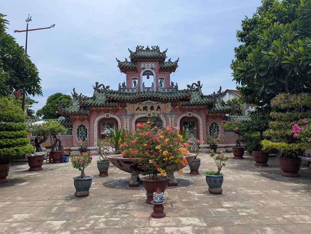 Hoi Quan Phuoc Kien, Hoi An Pink ancient temple with flower pots and bonsai trees in the foreground