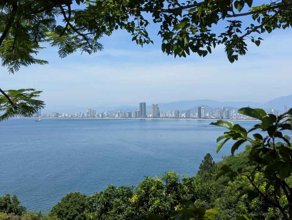 Views through the trees of the sea and Danang city in the distance