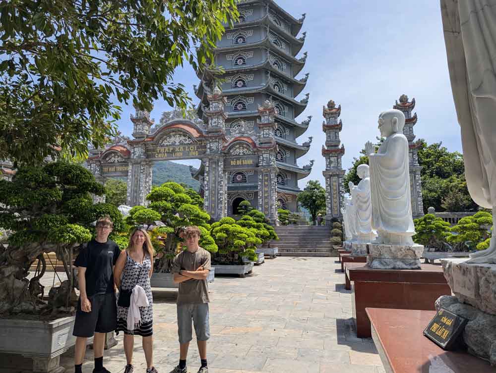 A woman and 2 teenagers in front of temples at the Linh Ung Pagoda, Danang