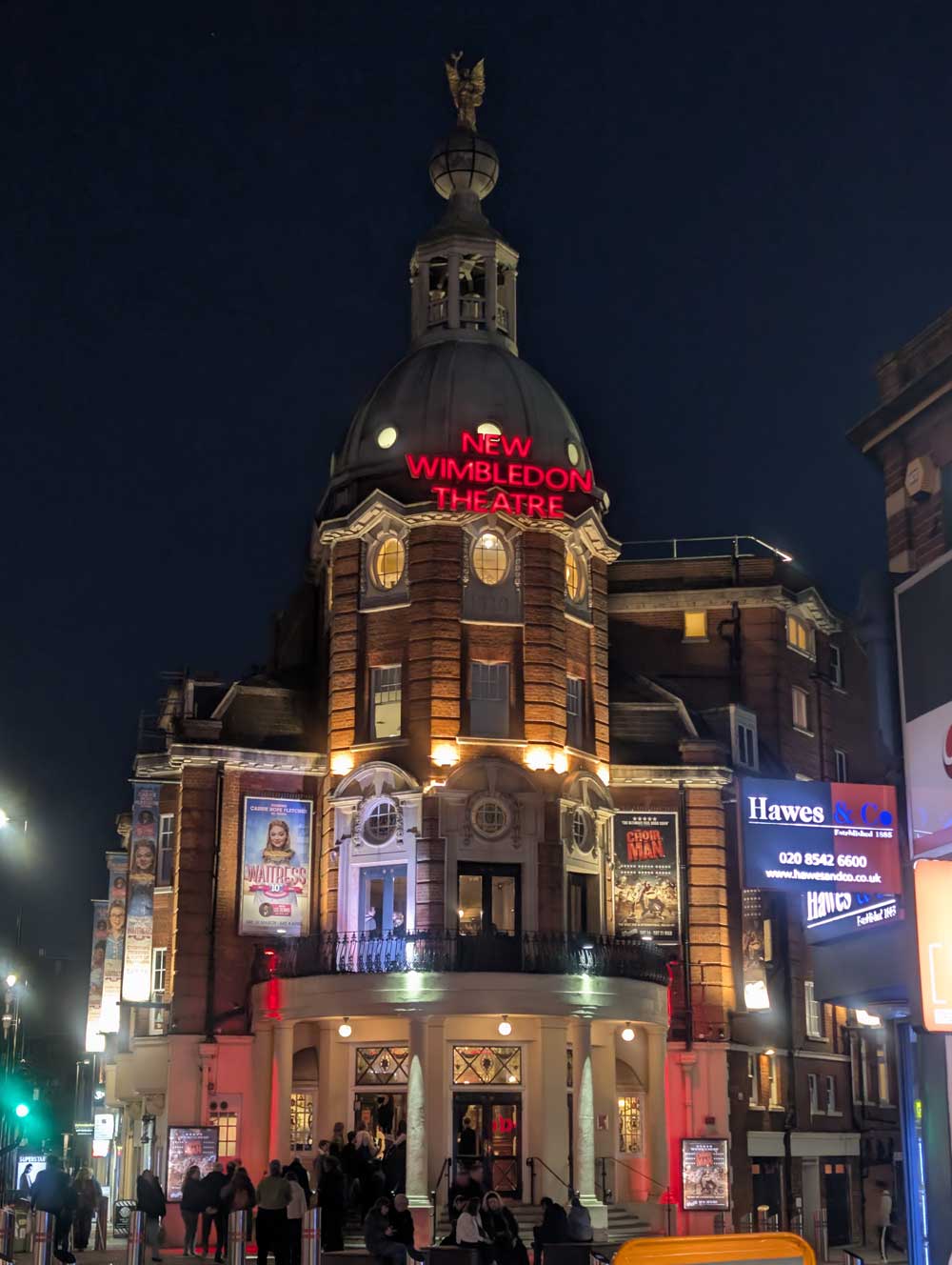 New Wimbledon Theatre at night with red neon sign on roof.