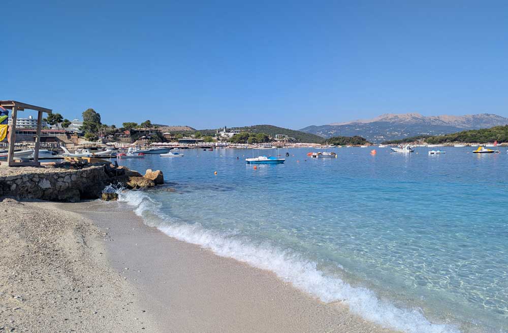 Boats on sea and waves lapping shore at Ksamil Beach, Albania