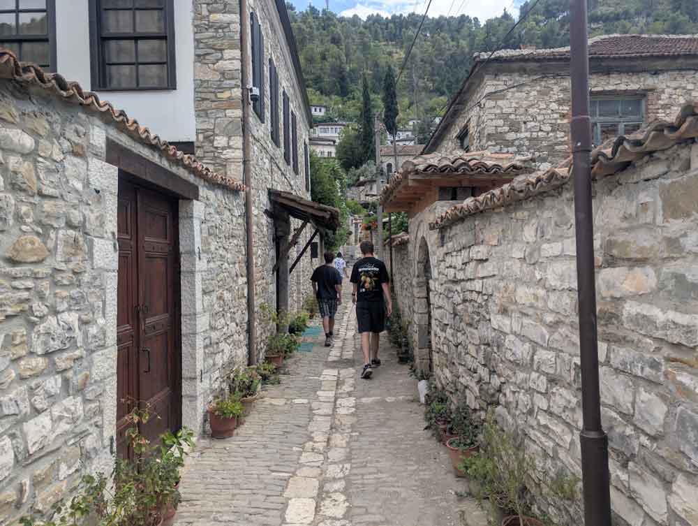 2 boys in an alley with stone walls in the backstreets of Gorica, Berat