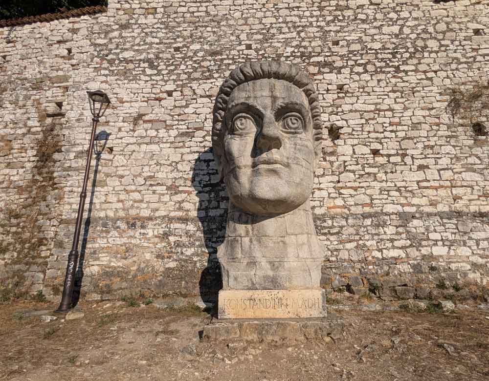 Large stone head next to lamp post at Berat Castle