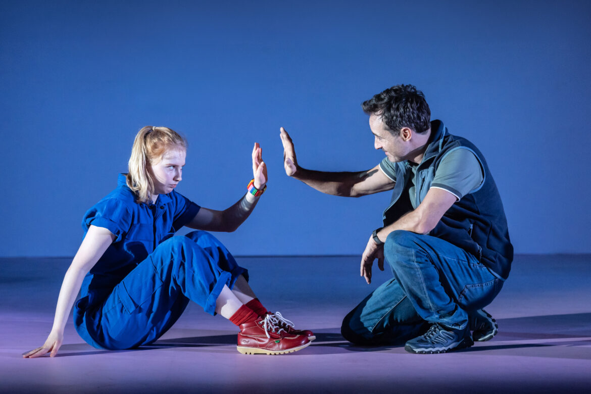 child with her father holding hands up towards each other in The Curious Incident of the Dog in the Night-Time play
