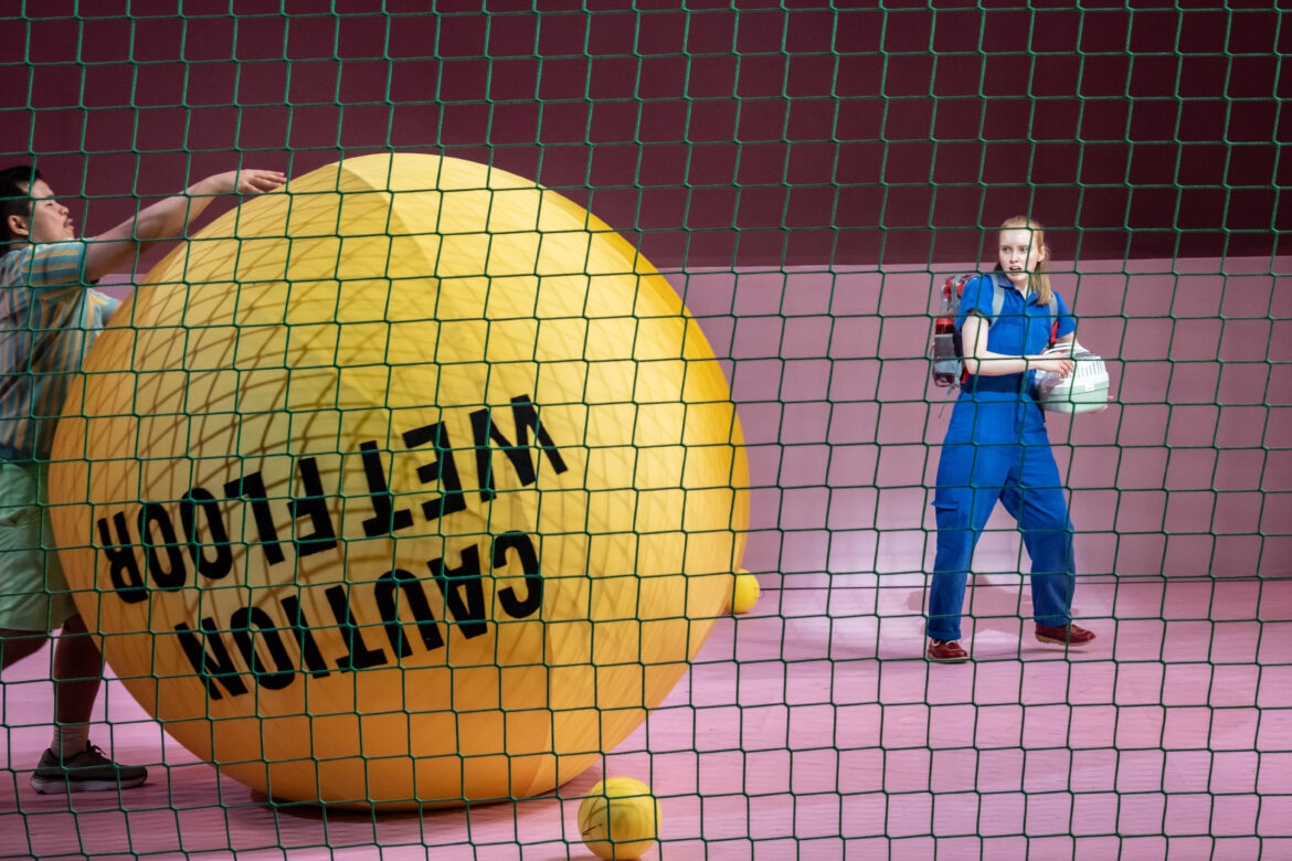 Girl on an imaginary tennis court with a giant yellow ball and lots of smaller balls