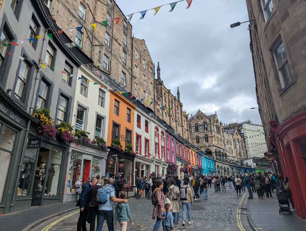 Victoria Street with a curved row of painted buildings, bunting and people milling about