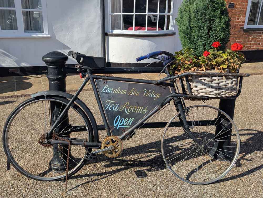 Vintage bike with basket full of flowers advertising the Lavenham Blue Vintage Tea Rooms in Lavenham